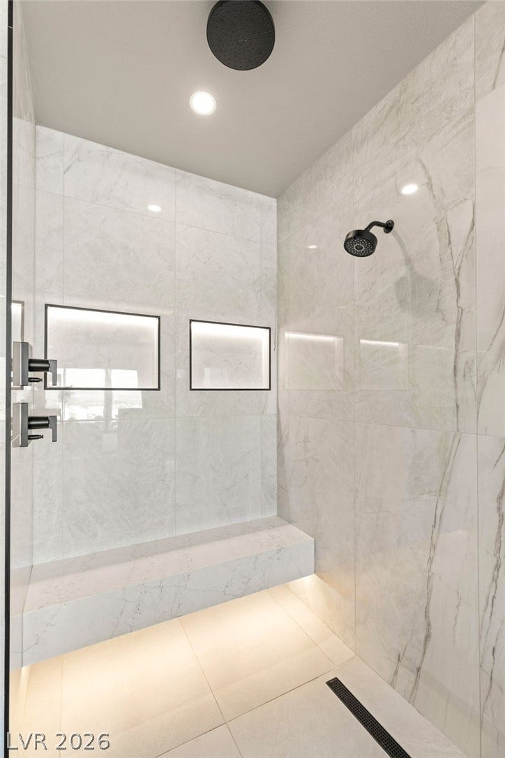 Marble-clad shower with integrated bench seating and dual shower heads for a luxurious bathing experience.