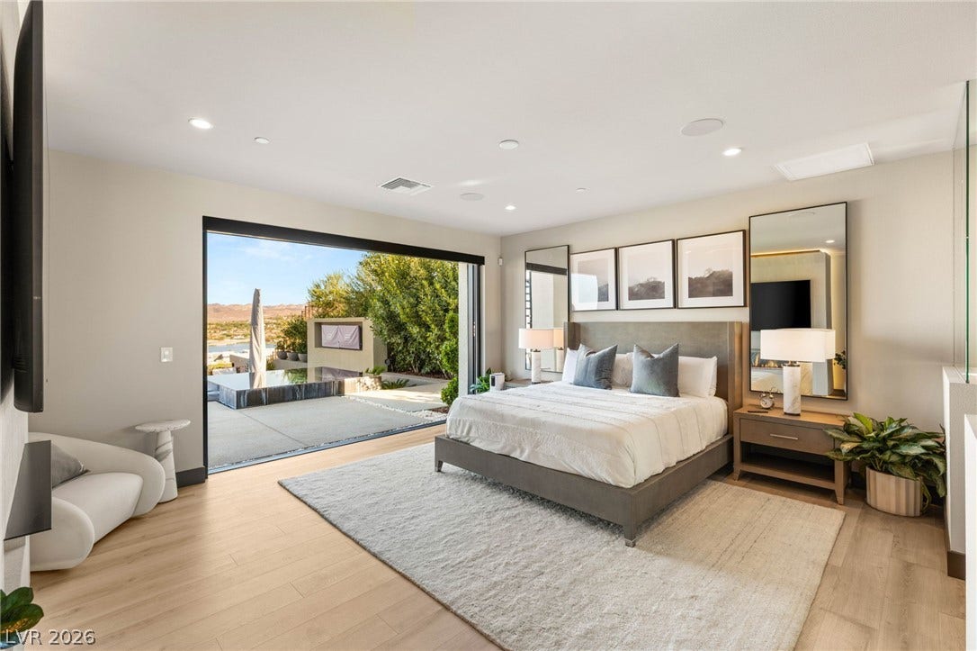 An open-concept primary bedroom with broad wooden floors and expansive outdoor access.
