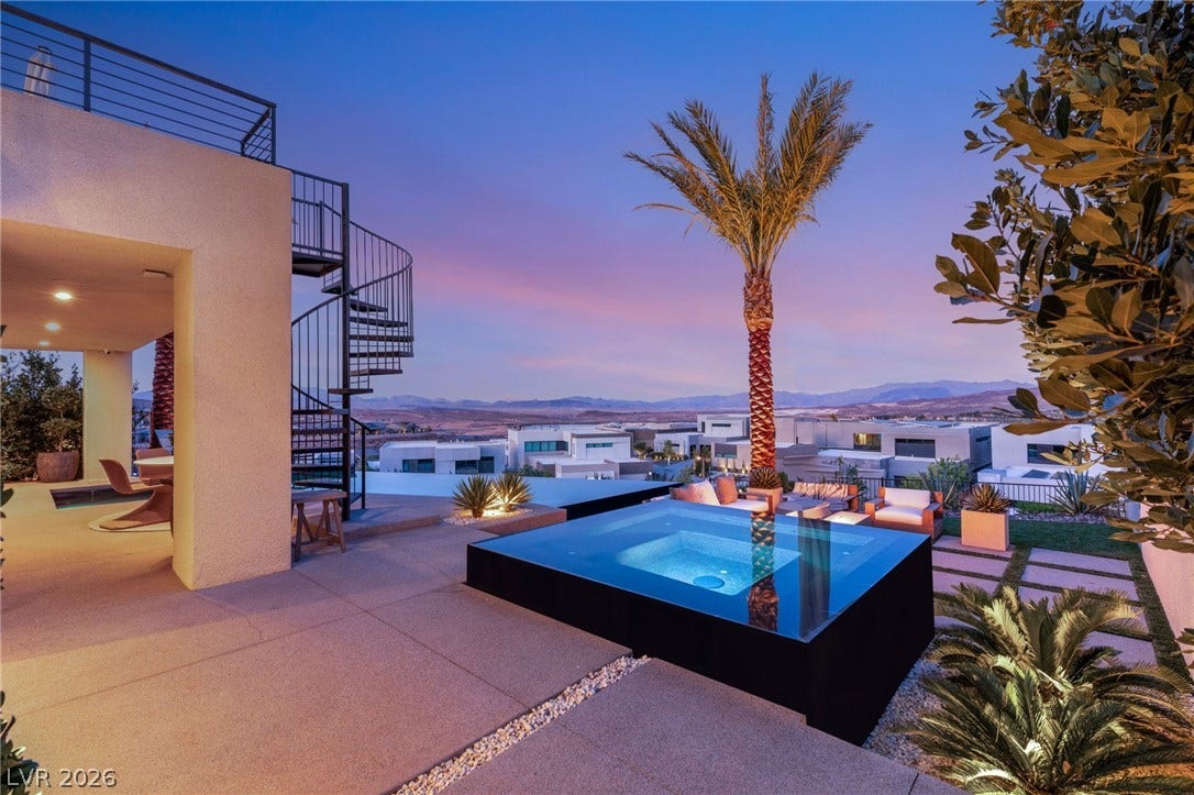 Dramatic spiral staircase leads to an upper balcony, complementing the chic outdoor pool and distant mountain views.
