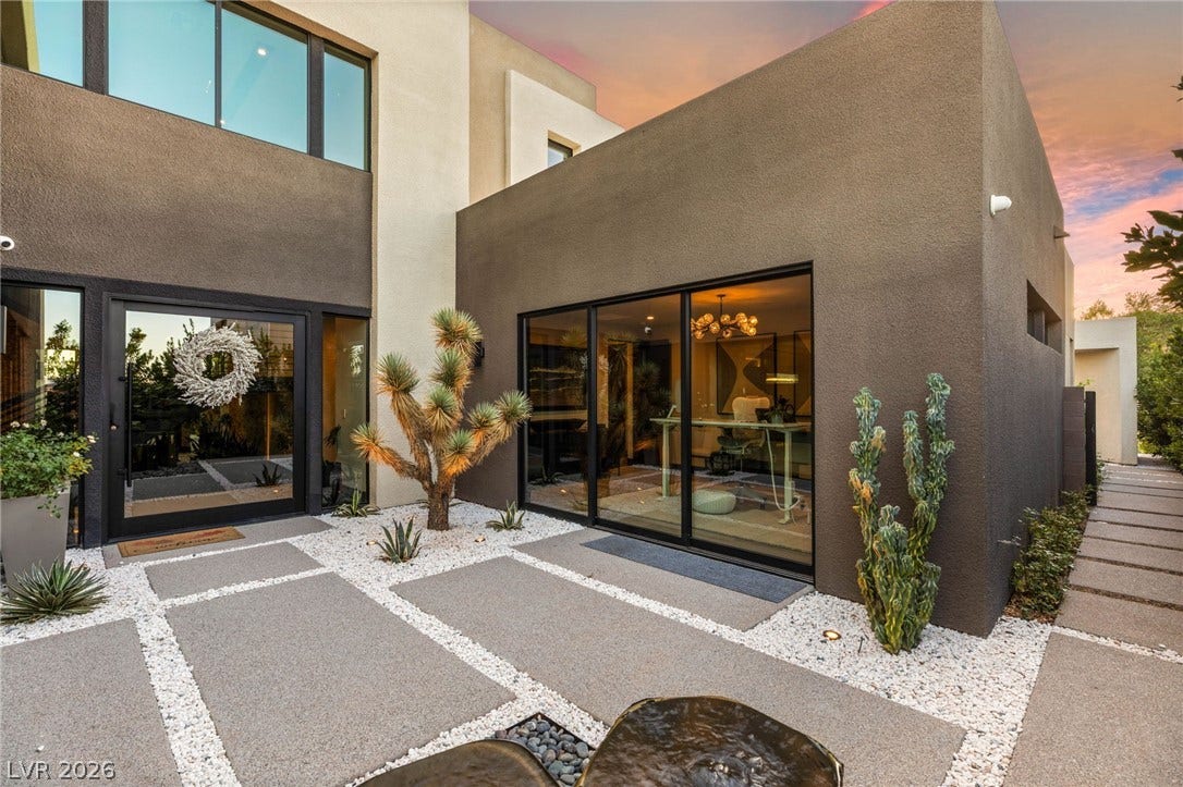 Modern desert landscaping frames the grand entrance of this architectural residence.