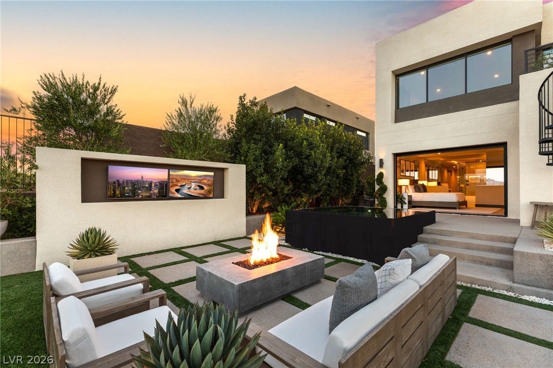An inviting outdoor living space features a modern fire pit, integrated entertainment center, and sleek patio furniture.