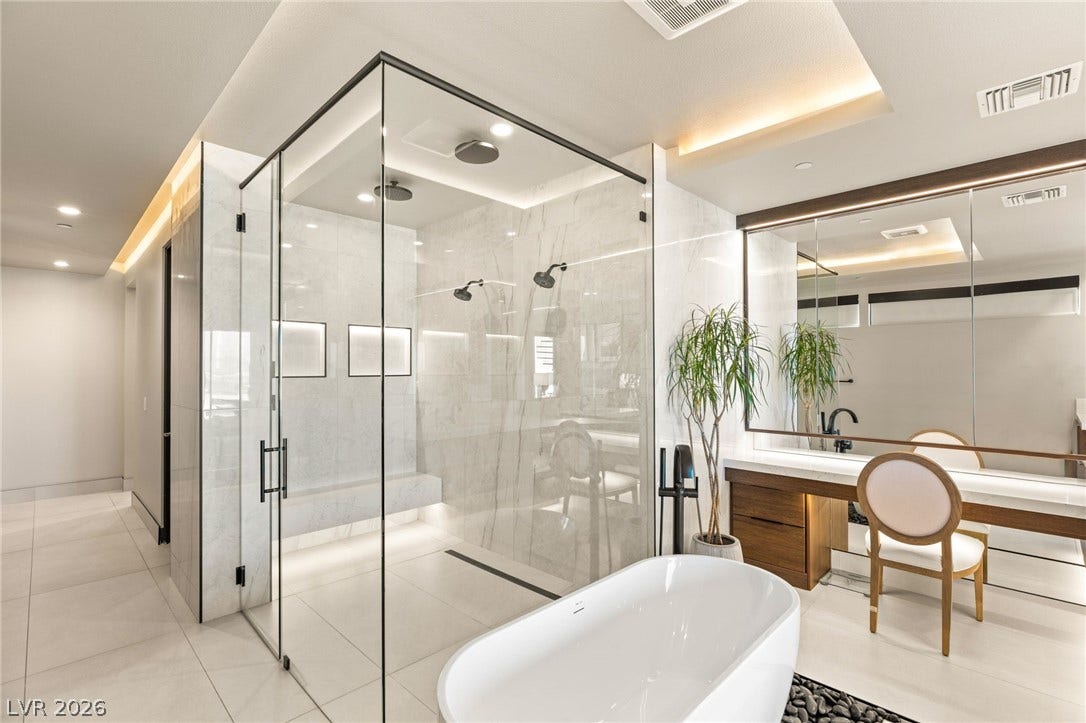 Indulge in a spa-like retreat with this well-lit bathroom featuring a spacious walk-in shower and freestanding tub.