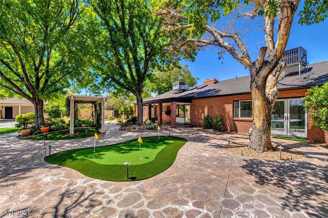 2001 Silver Avenue, Las Vegas, NV 89102 Mature trees shade a patterned stone patio and private putting green behind a brick home.