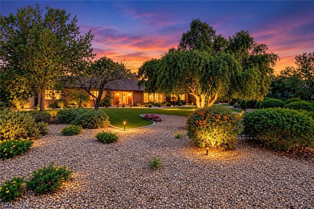 2001 Silver Avenue, Las Vegas, NV 89102 Lush landscaping and custom outdoor lighting frame the sprawling ranch-style exterior under vibrant sunset skies.