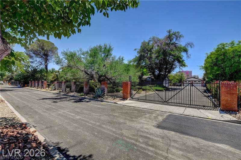 2001 Silver Avenue, Las Vegas, NV 89102 Secure gated entry features a paved driveway framed by brick pillars and mature landscaping.
