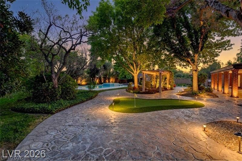 2001 Silver Avenue, Las Vegas, NV 89102 Stone pavers wind past a putting green and mature trees toward a private pool.