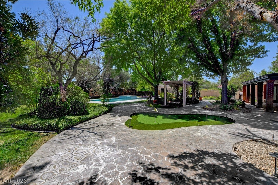 2001 Silver Avenue, Las Vegas, NV 89102 Mature trees shade a patterned stone patio featuring a private putting green and distant swimming pool.
