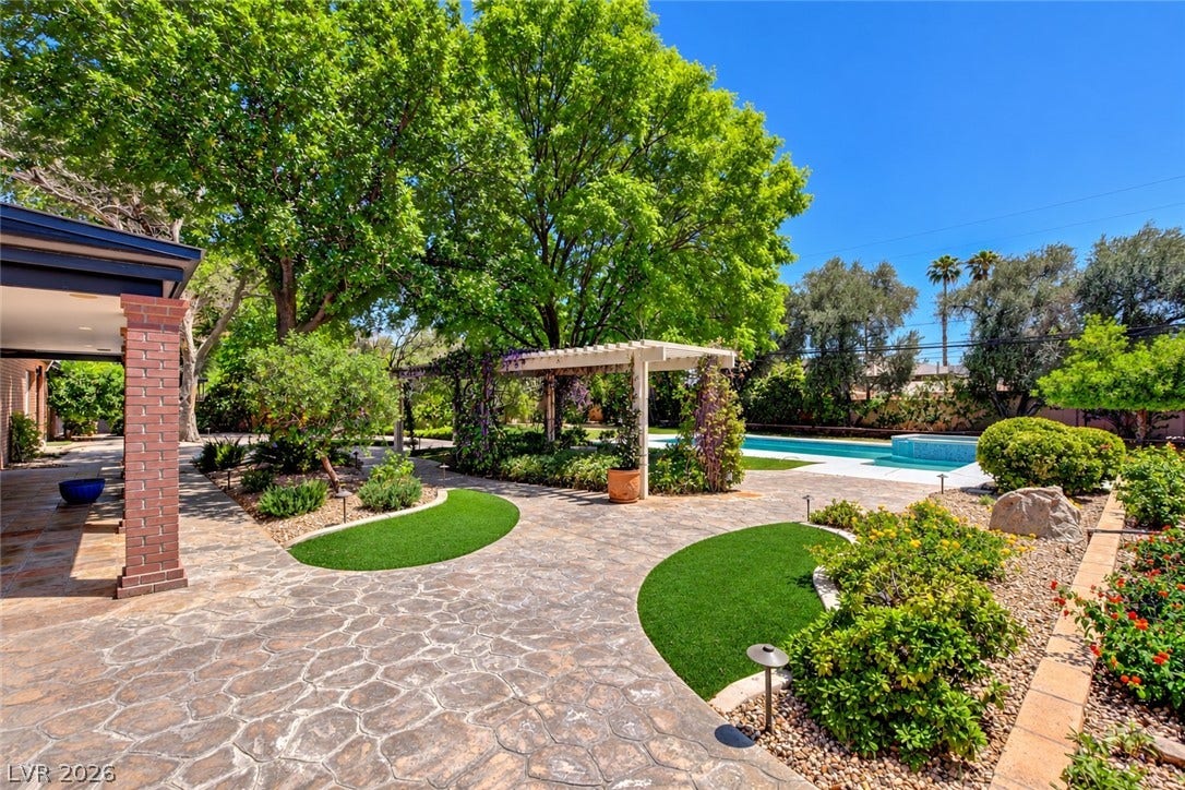 2001 Silver Avenue, Las Vegas, NV 89102 Stoned paved pathways wind through manicured grounds leading to a swimming pool under clear blue skies.