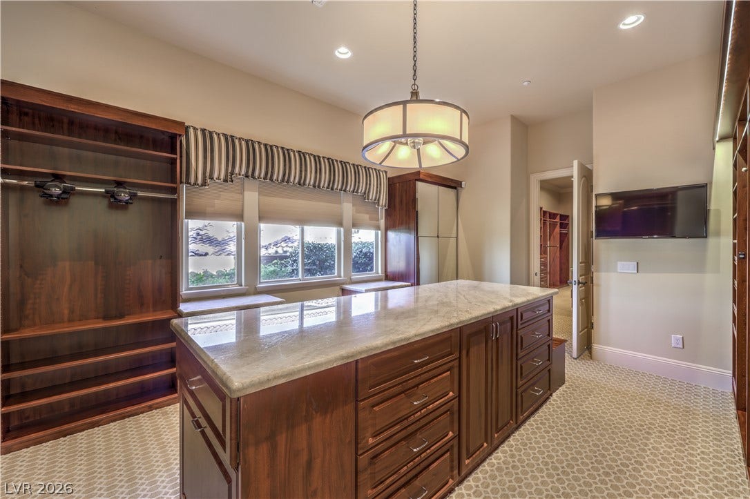 16 Anthem Pointe Court, Henderson, NV 89052 Rich wood built-ins and a polished stone-topped island define this expansive dressing room.