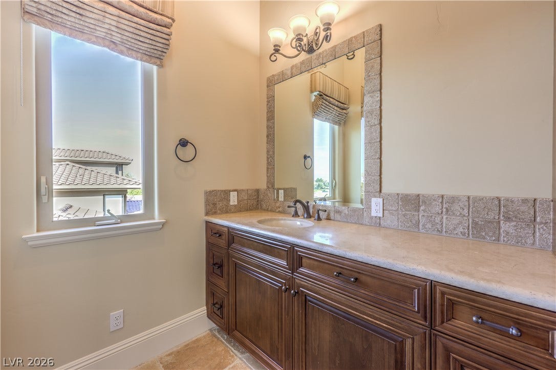 16 Anthem Pointe Court, Henderson, NV 89052 A spacious stone countertop crowns the dark wood vanity in this sunlit bathroom.