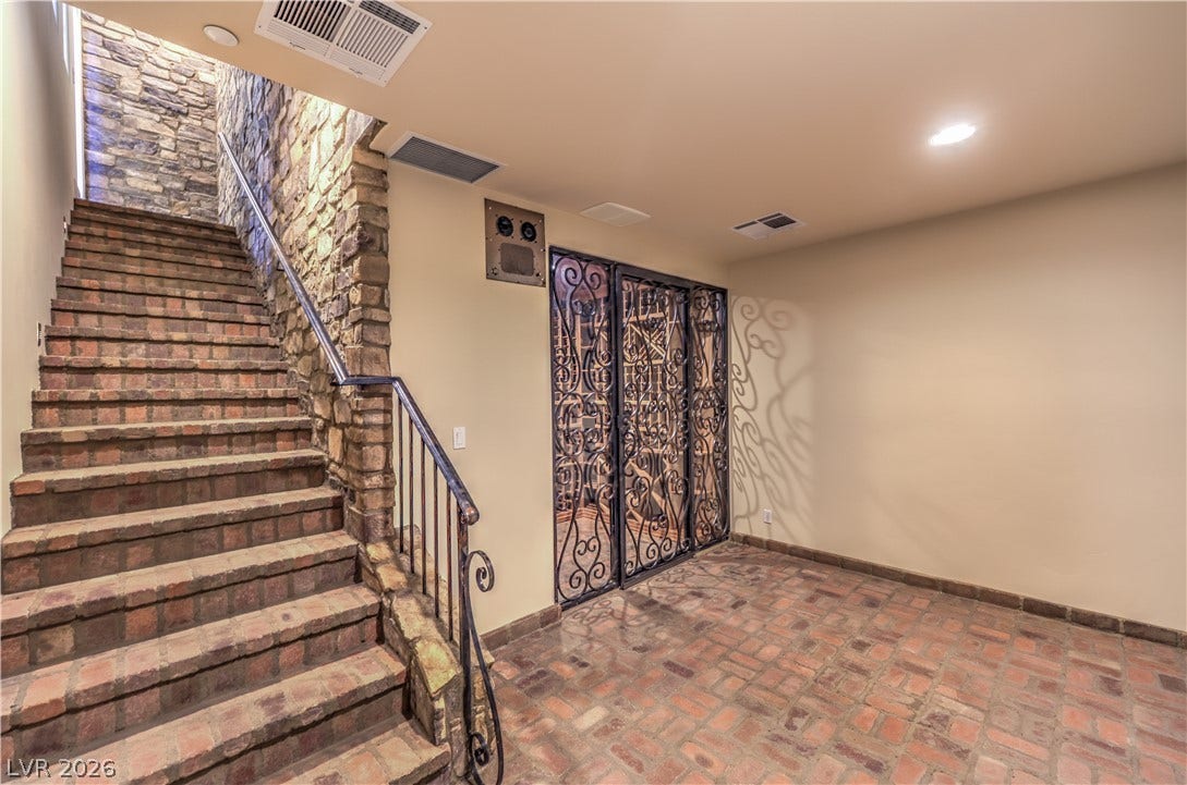 16 Anthem Pointe Court, Henderson, NV 89052 An elegant brick staircase and coordinating brick floor ascend alongside a rustic stone accent wall.