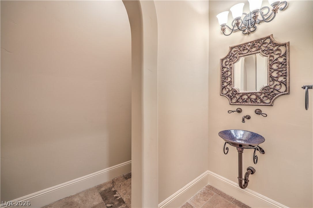 16 Anthem Pointe Court, Henderson, NV 89052 An elegant arched doorway leads into this unique powder room with stone tile flooring.