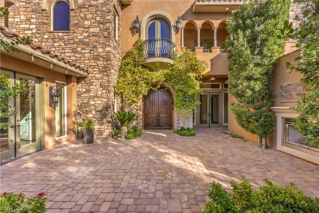 16 Anthem Pointe Court, Henderson, NV 89052 An inviting stone-accented courtyard featuring elegant brick pavers leads to arched entryways.