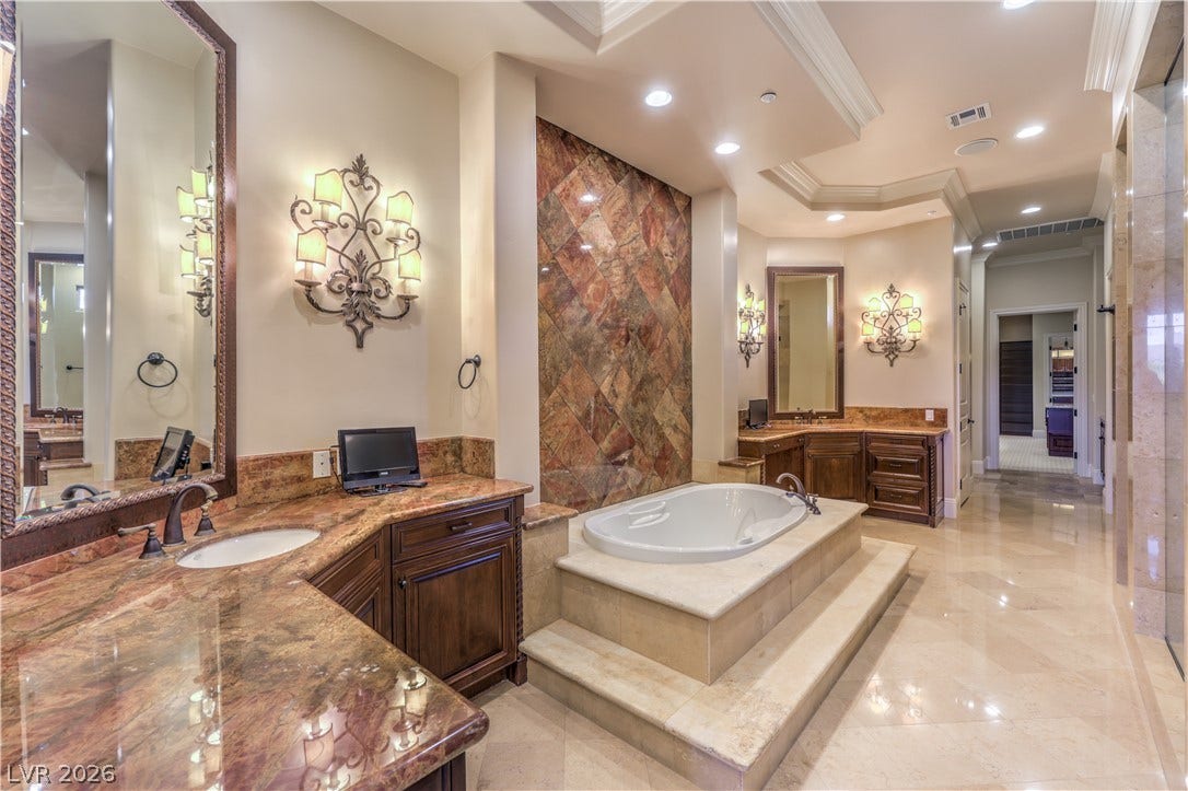 16 Anthem Pointe Court, Henderson, NV 89052 Gleaming stone tile flooring and a soaking tub define this elegant primary bathroom.