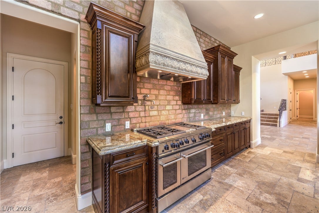 16 Anthem Pointe Court, Henderson, NV 89052 Rich wood cabinetry and a brick accent wall frame the premium professional-grade gas range.