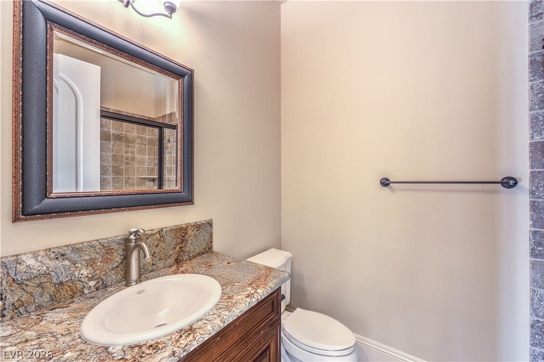 16 Anthem Pointe Court, Henderson, NV 89052 Richly veined granite counters pair with a framed mirror in this modern powder room.