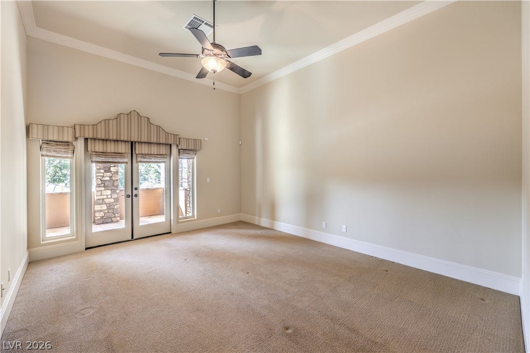 16 Anthem Pointe Court, Henderson, NV 89052 High ceilings and classic crown molding elevate this carpeted bedroom featuring French doors.