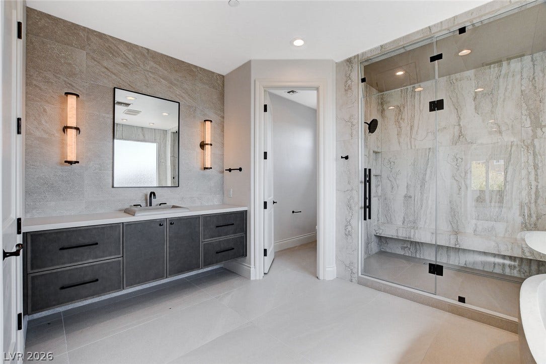 84 Kittansett Loop, Henderson, NV 89052 Fine stone tile and sleek modern cabinetry elevate this luxurious primary bath.