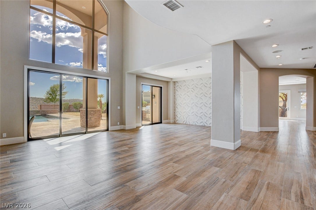 84 Kittansett Loop, Henderson, NV 89052 Towering windows frame poolside views, illuminating the wood-look tile flooring and modern open layout.