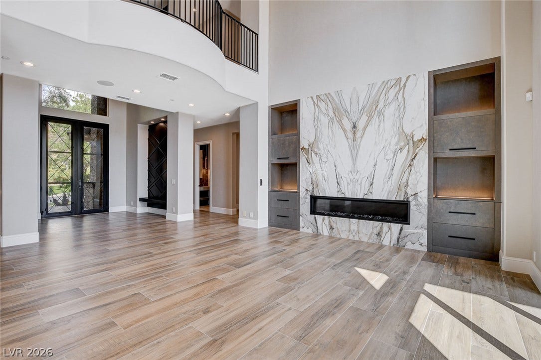 84 Kittansett Loop, Henderson, NV 89052 Double-height ceilings frame a striking marble-clad linear fireplace flanked by custom built-in shelving.
