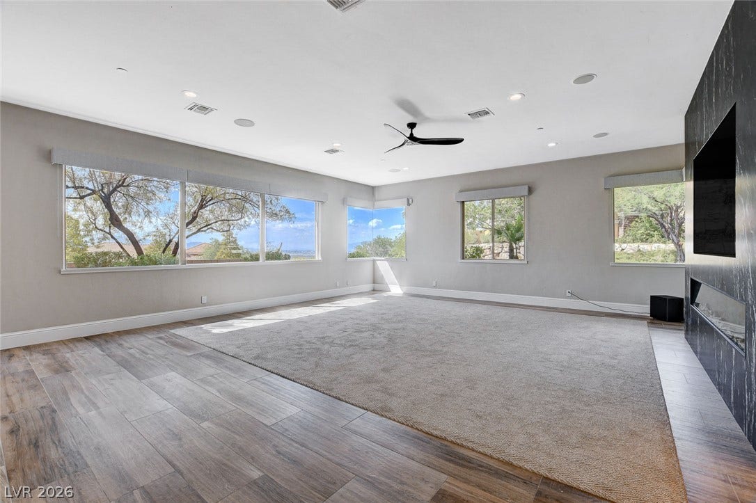 84 Kittansett Loop, Henderson, NV 89052 Numerous windows frame serene outdoor views in this spacious living area with hardwood flooring.