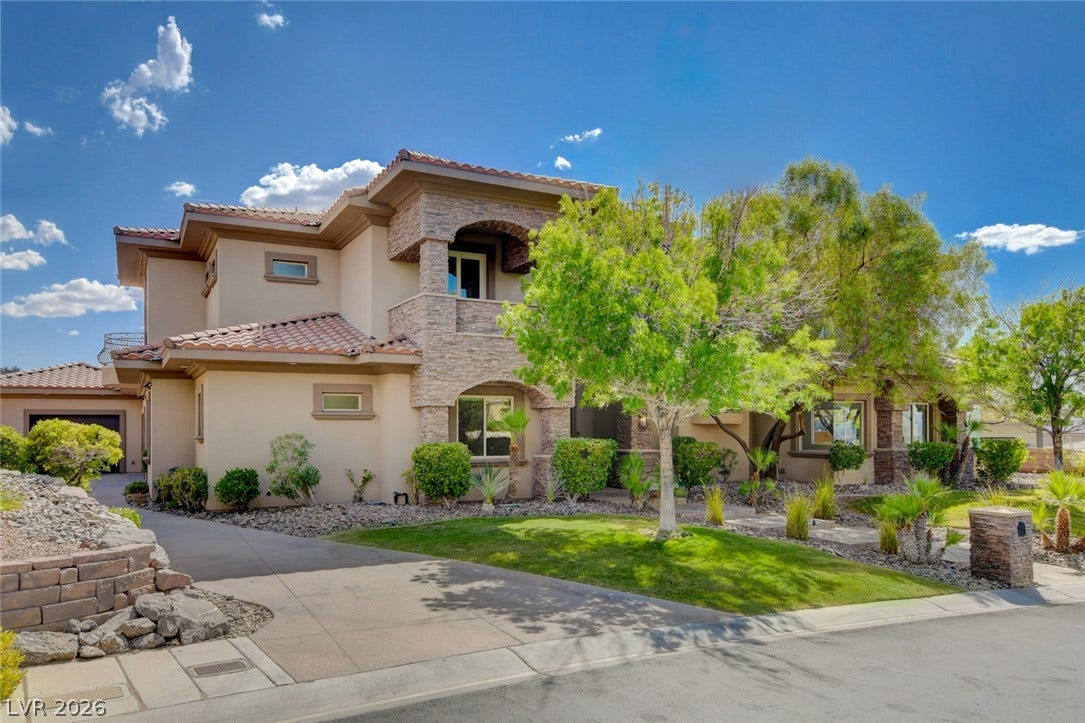 84 Kittansett Loop, Henderson, NV 89052 Mediterranean-inspired architecture showcases textured stone accents and a classic tile roof under sunny skies.