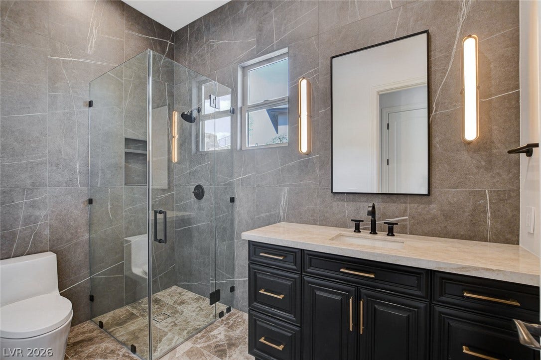 84 Kittansett Loop, Henderson, NV 89052 Floor-to-ceiling stone tile and a frameless glass shower define this contemporary bathroom.