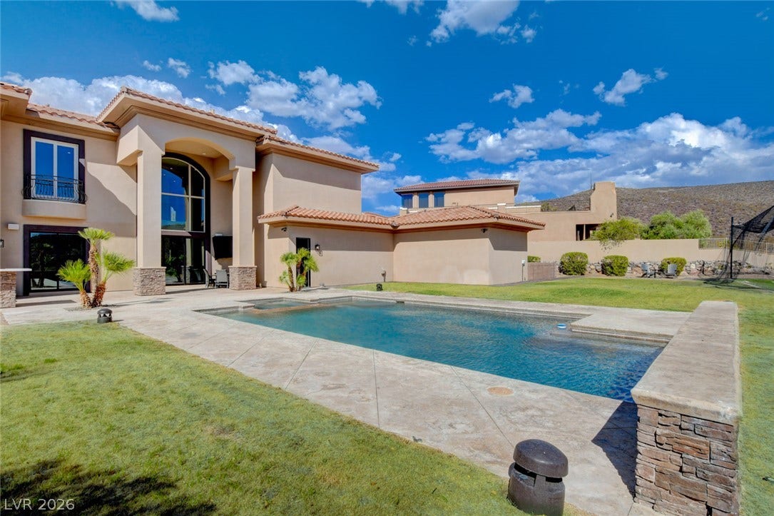 84 Kittansett Loop, Henderson, NV 89052 An inviting backyard swimming pool rests alongside manicured green lawns and elegant Mediterranean architecture.
