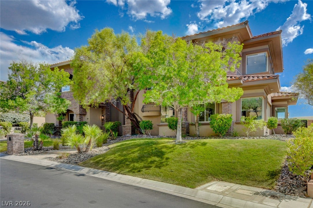 84 Kittansett Loop, Henderson, NV 89052 Lush landscaping frames the elegant exterior showcasing classic stone accents and a tile roof.