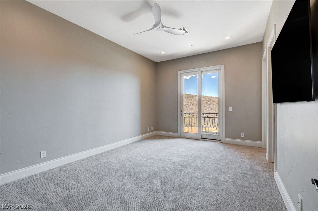 84 Kittansett Loop, Henderson, NV 89052 Sliding glass doors frame serene hillside views from this carpeted bedroom.