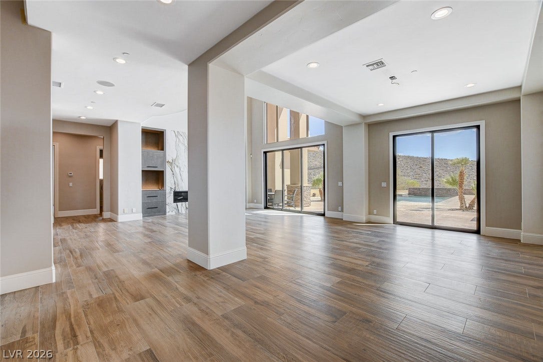 84 Kittansett Loop, Henderson, NV 89052 Sliding glass doors frame pool views in this open-concept room with rich wood-look flooring.