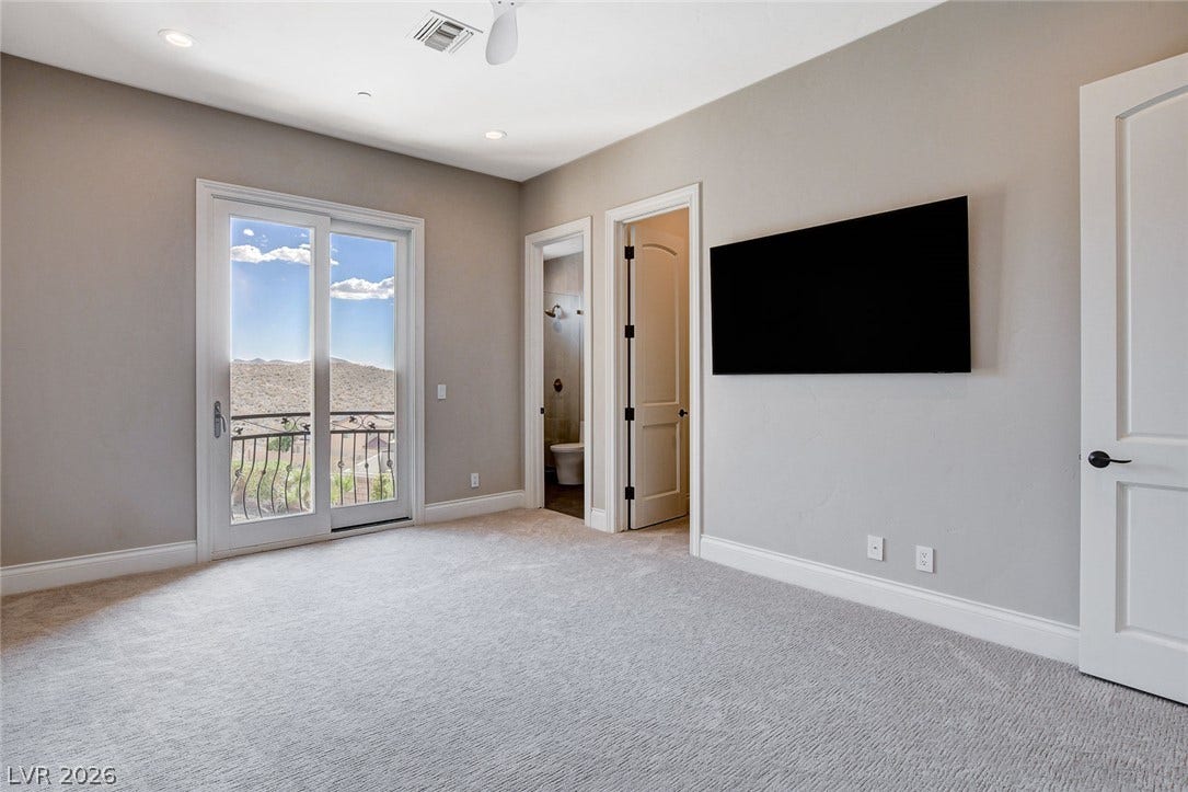 84 Kittansett Loop, Henderson, NV 89052 Sliding glass doors open to a private balcony showcasing distant mountain views.