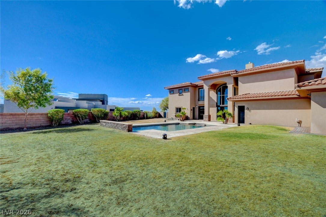 84 Kittansett Loop, Henderson, NV 89052 A spacious green lawn stretches alongside a private swimming pool behind this stucco home.