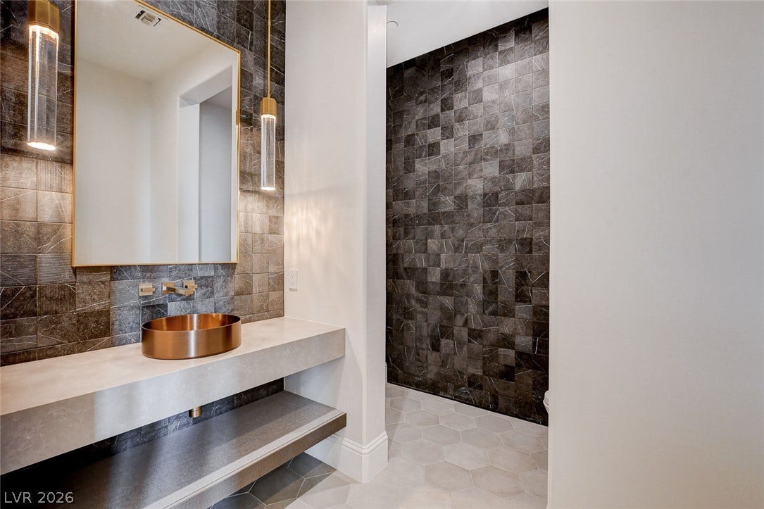 84 Kittansett Loop, Henderson, NV 89052 A floating concrete vanity meets textured stone walls and hexagonal tile flooring in this powder room.