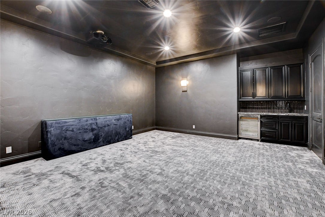 84 Kittansett Loop, Henderson, NV 89052 Textured walls and patterned carpeting define this moody home media room with integrated wet bar.
