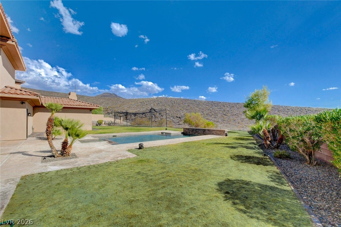 84 Kittansett Loop, Henderson, NV 89052 An inviting backyard pool overlooks rolling hills under a wide blue sky.