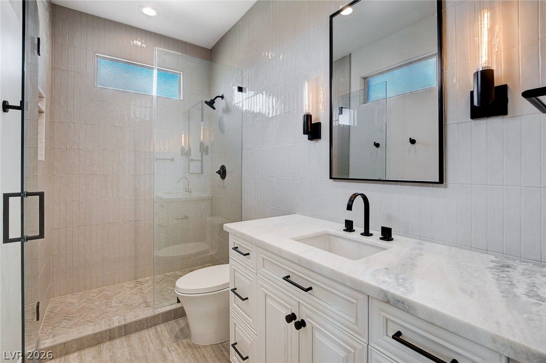 84 Kittansett Loop, Henderson, NV 89052 A glass-enclosed walk-in shower complements the marble-topped vanity in this modern bathroom.