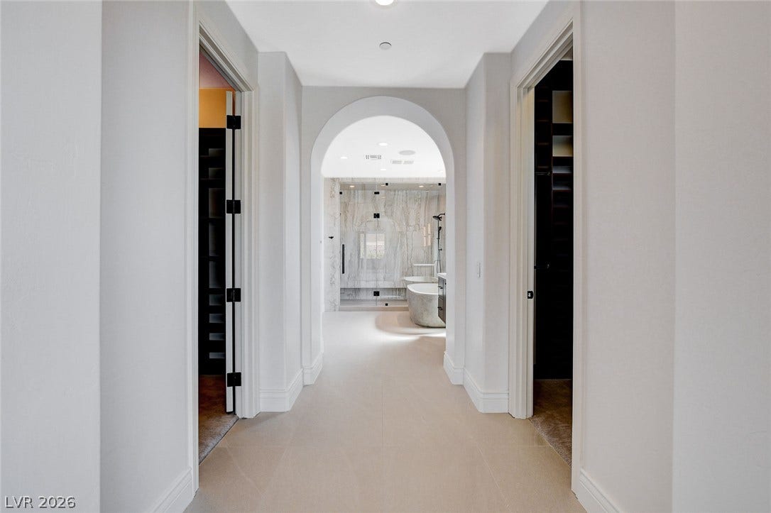 84 Kittansett Loop, Henderson, NV 89052 An elegant arched doorway leads into a modern primary bathroom with stone finishes.