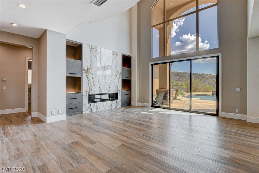 84 Kittansett Loop, Henderson, NV 89052 Towering ceilings and sliding glass doors frame tranquil desert views from this open living space.