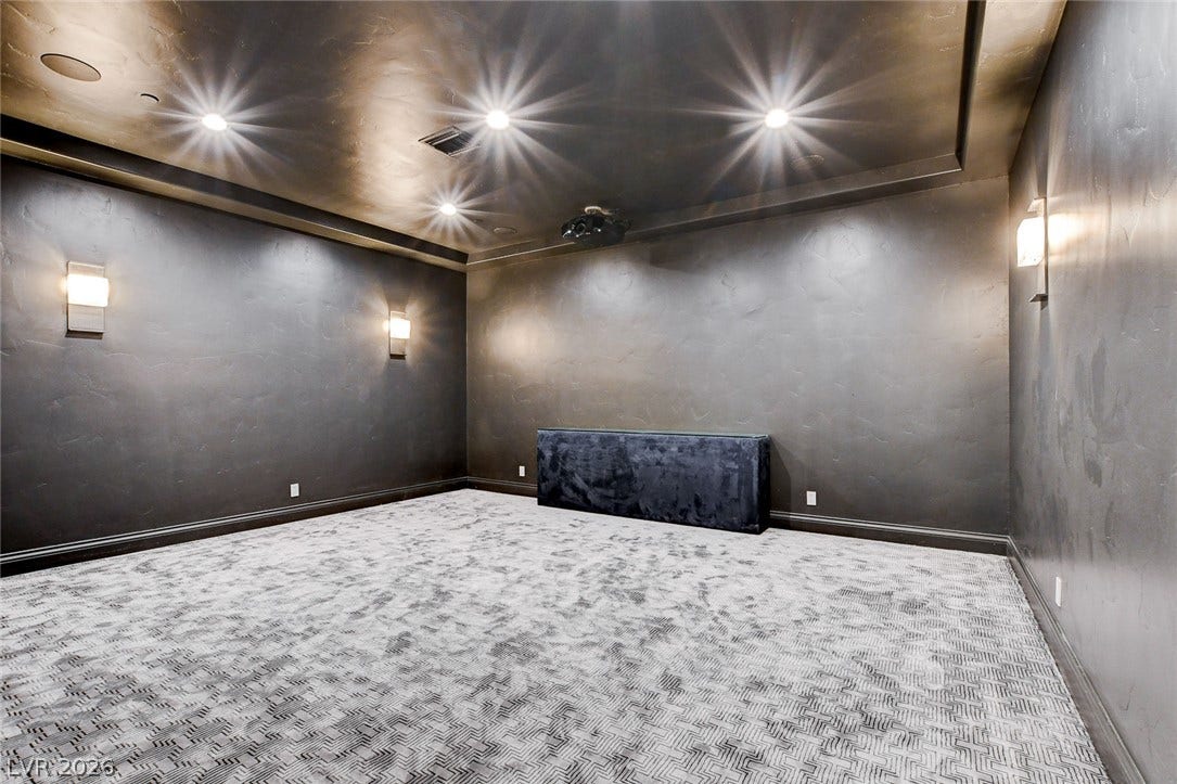 84 Kittansett Loop, Henderson, NV 89052 A spacious home theater room boasts textured walls and patterned carpeting below recessed lighting.