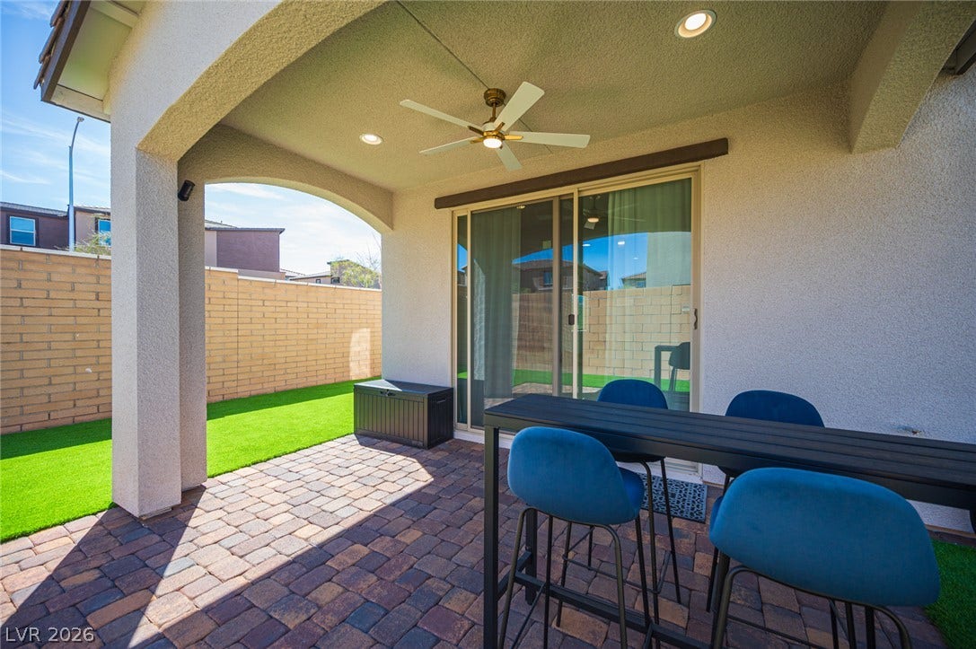 320 Della Pergola Place, Henderson, NV 89015 An inviting covered patio features neat paver flooring alongside a grassy yard and privacy walls.
