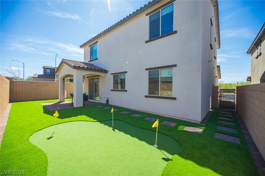 320 Della Pergola Place, Henderson, NV 89015 A private backyard features a custom putting green alongside a paved patio and stone privacy walls.