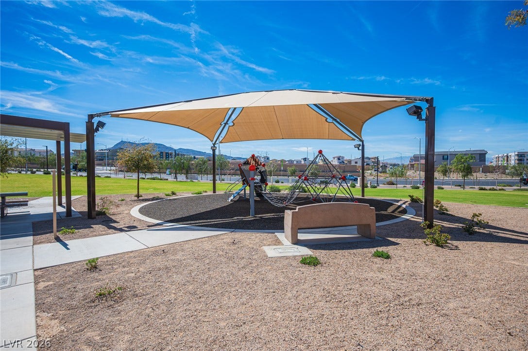 320 Della Pergola Place, Henderson, NV 89015 Concrete walkways lead to a modern neighborhood recreation space featuring a shaded play structure.