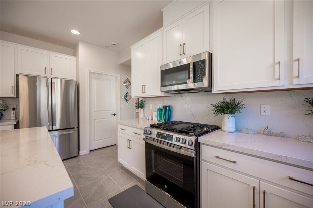 320 Della Pergola Place, Henderson, NV 89015 Gleaming stone countertops and stainless steel appliances elevate this bright culinary space.