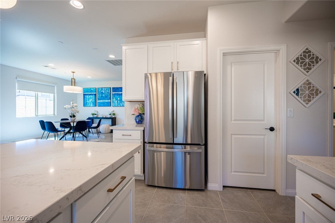 320 Della Pergola Place, Henderson, NV 89015 Gleaming stone countertops and modern tile flooring define this bright, open kitchen space.