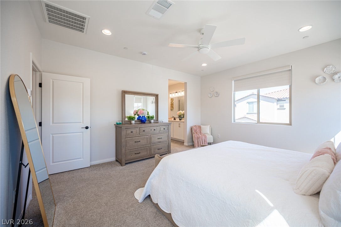 320 Della Pergola Place, Henderson, NV 89015 A spacious bedroom features soft carpet and an open doorway leading to the bathroom.