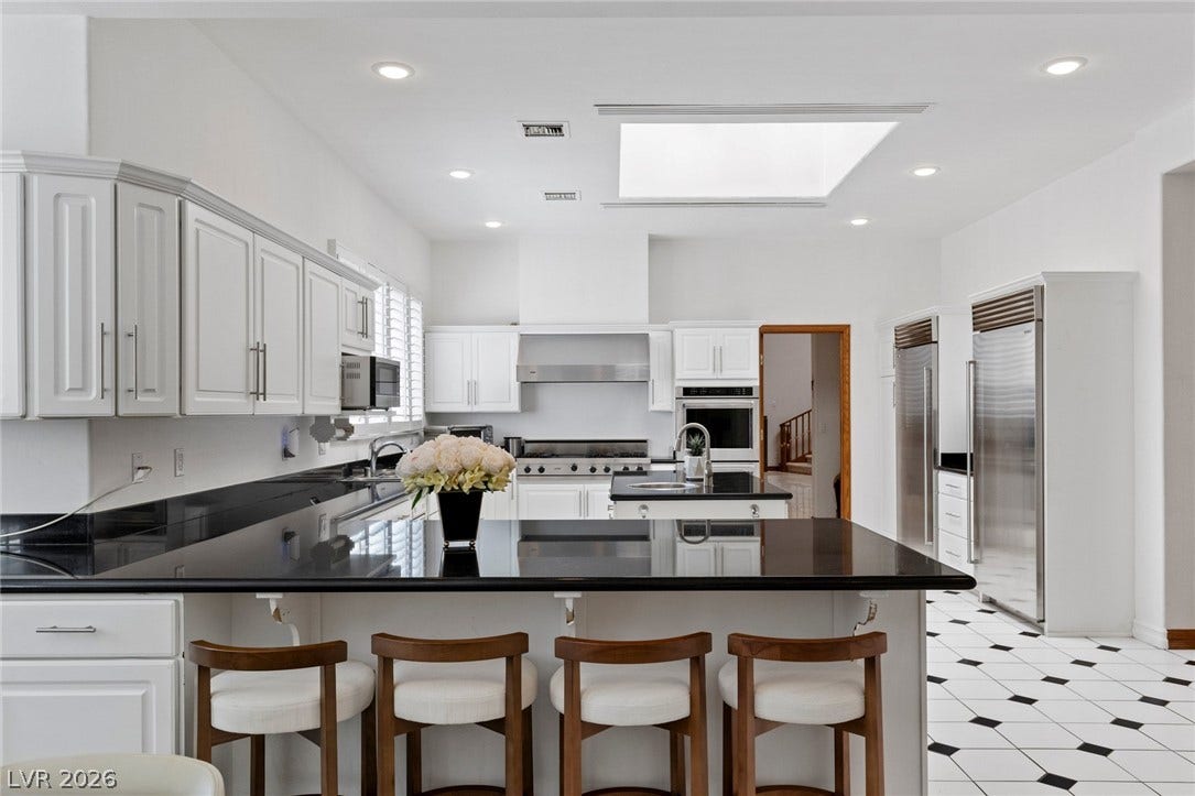Polished stone counters and a central skylight elevate this airy kitchen design.
