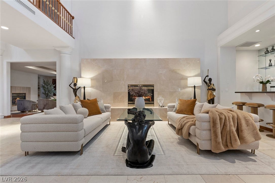 Towering ceilings and a grand stone fireplace define this majestic living space.