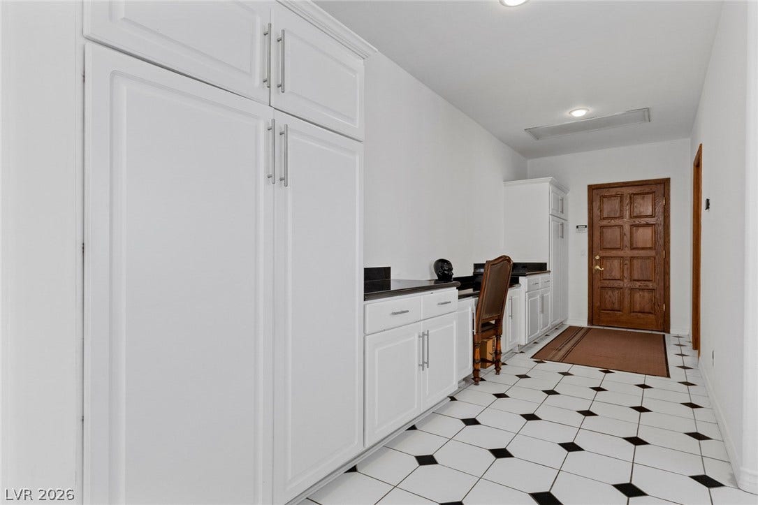 Graphic checkerboard tile floors lead past extensive built-in cabinetry toward a classic wood entry door.
