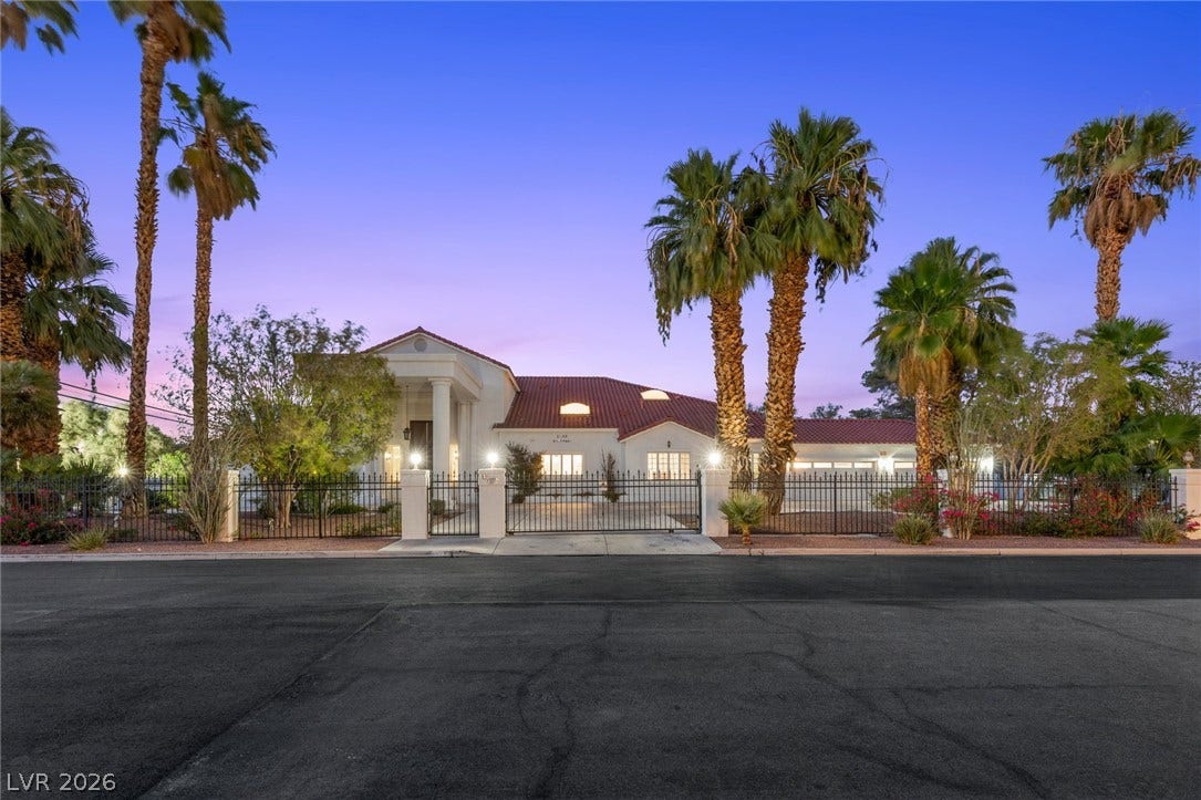 Stately pillars and tile roofing define this privately gated desert estate framed by mature palms.